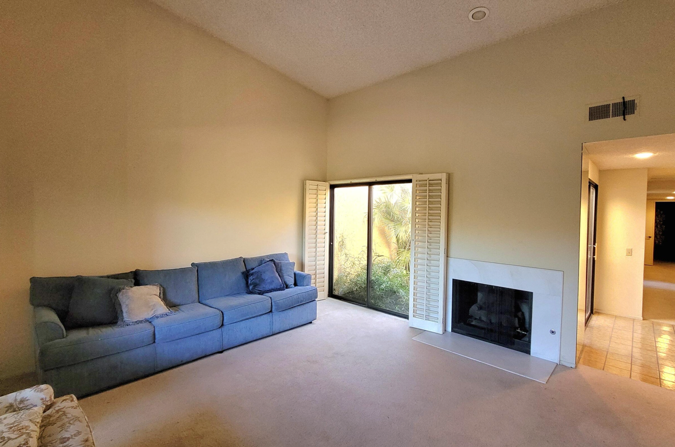 A living room with a blue couch and a fireplace