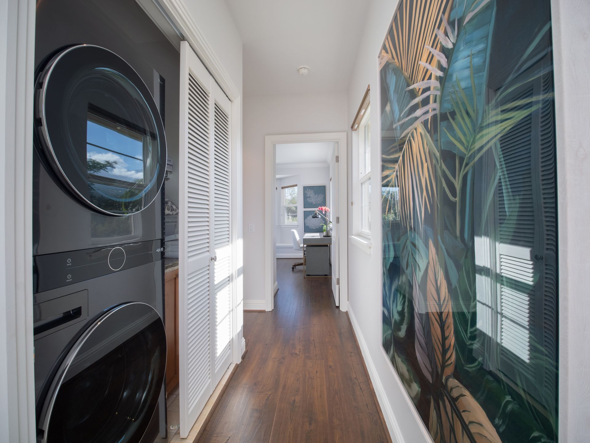A hallway with a washer and dryer and a picture on the wall.