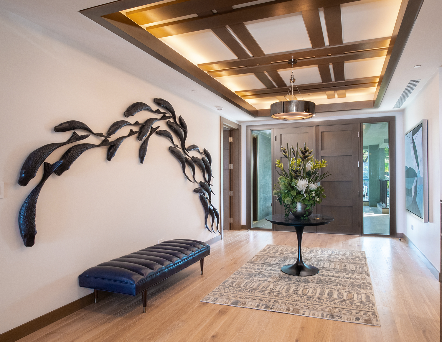 Entryway with dark fish sculpture, blue bench, wood floors, and a decorative ceiling.