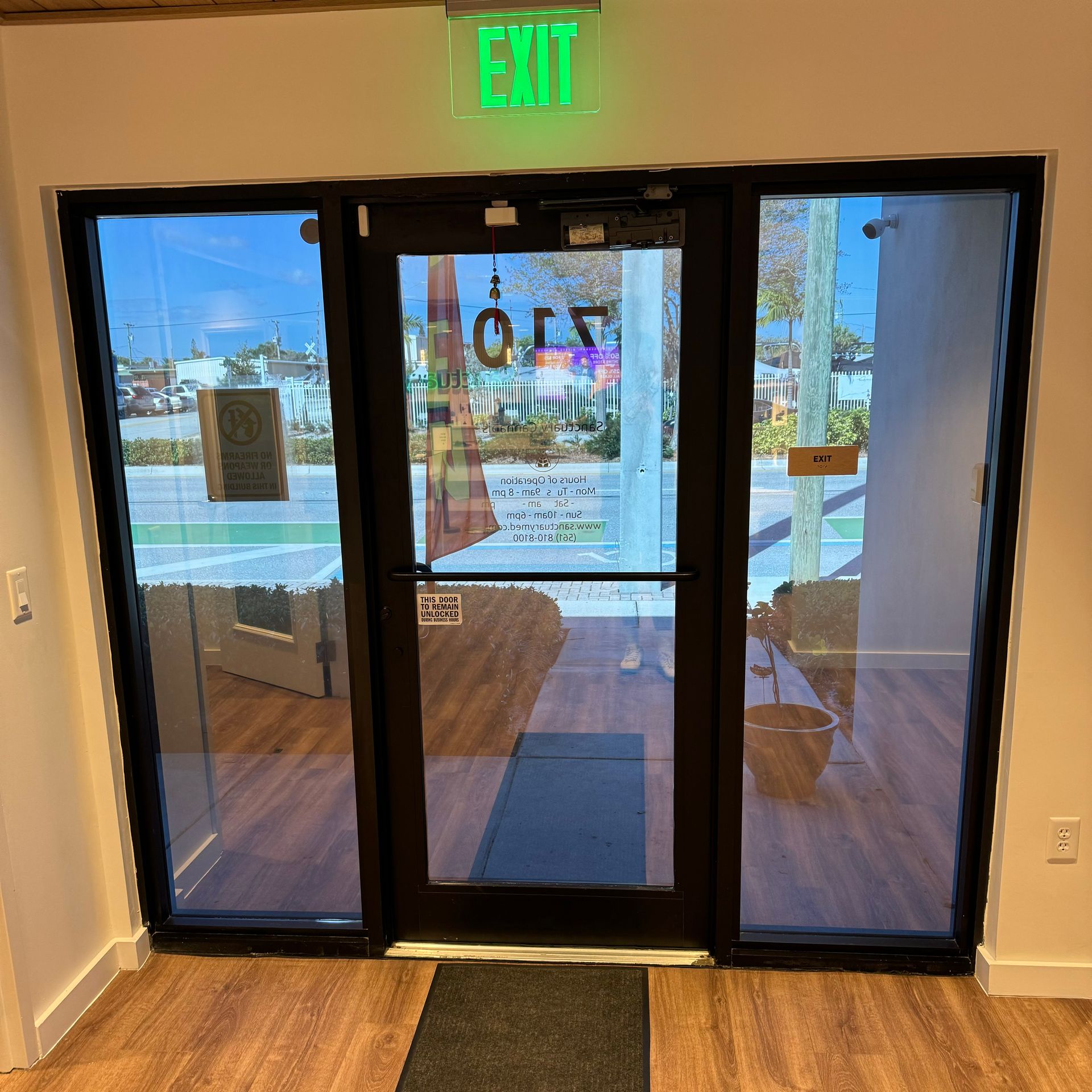 A green exit sign is above a glass door