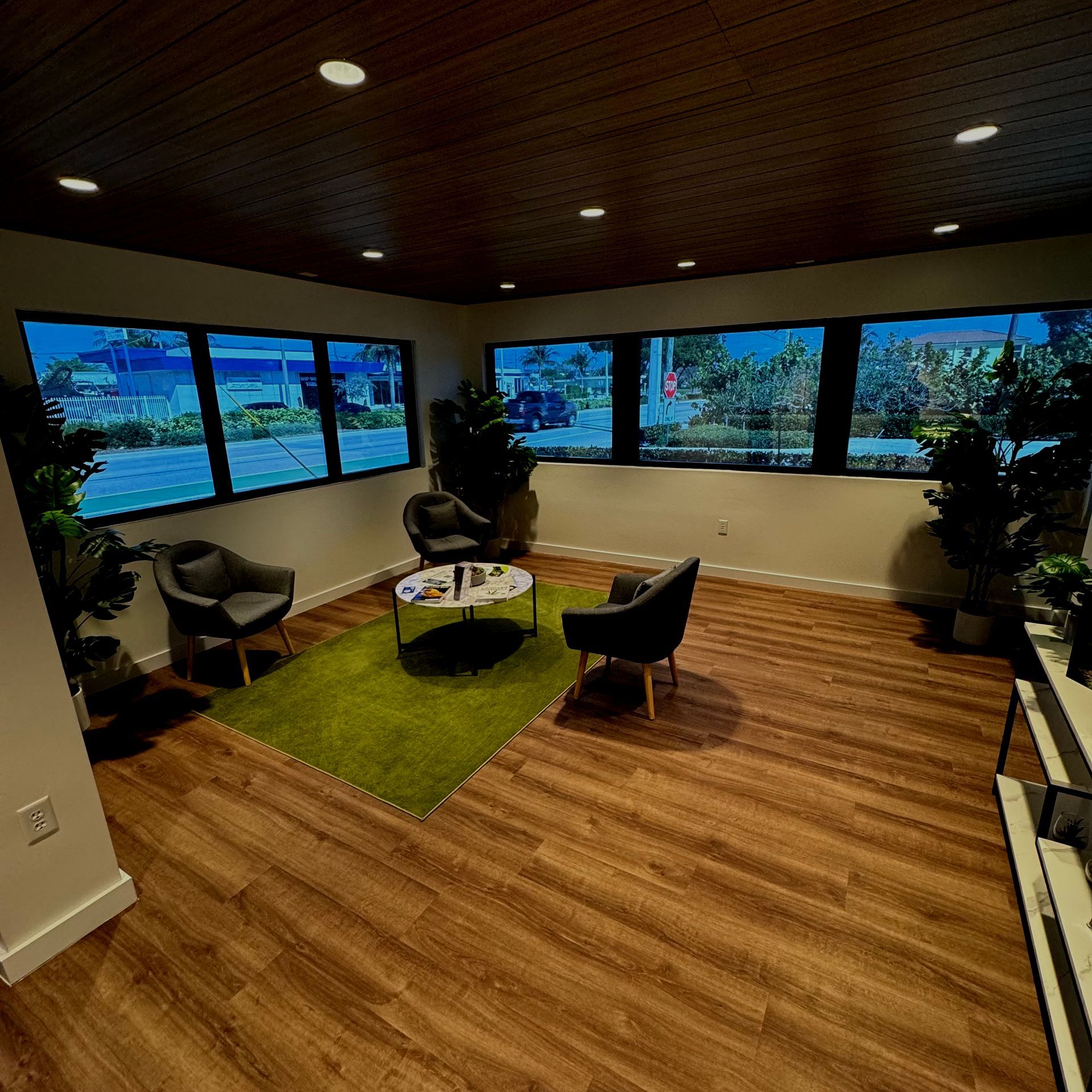 A living room with wooden floors , chairs , a table and a rug.