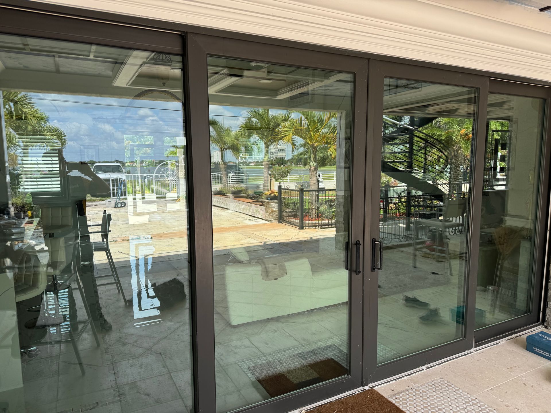 A large glass door leading to a living room with a staircase in the background.