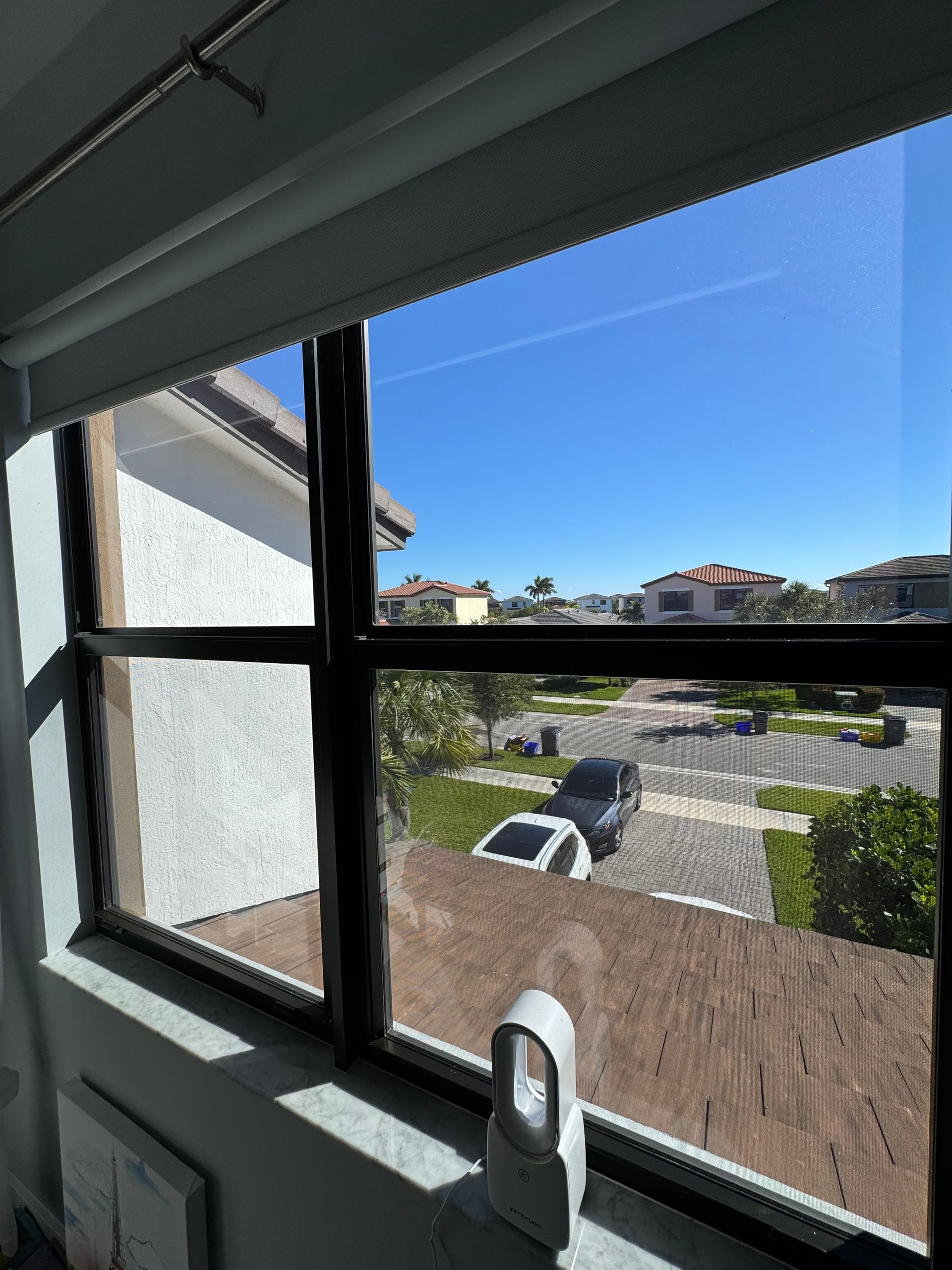 A window with a view of a residential area and a blue sky