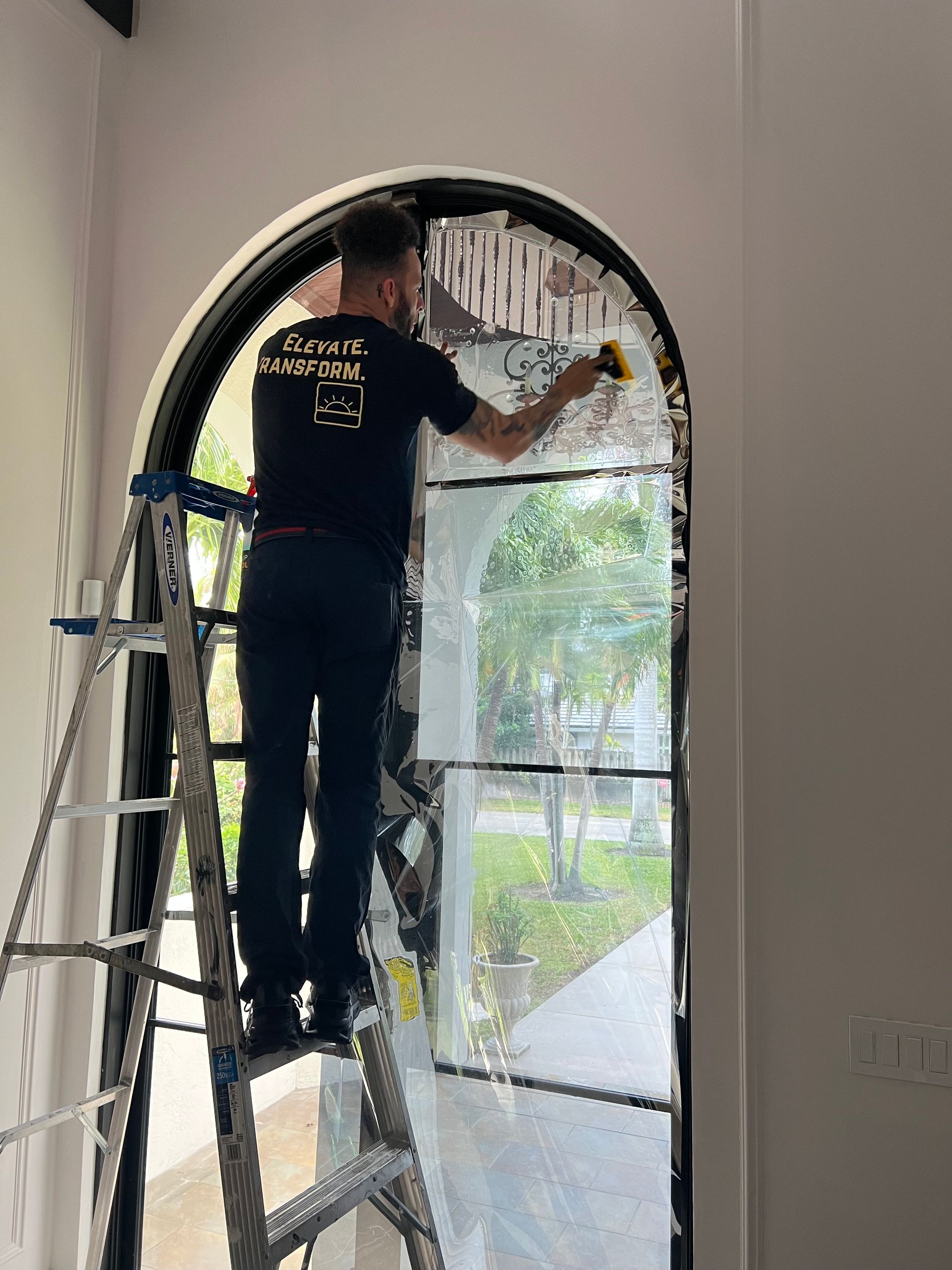 A man is standing on a ladder cleaning a window.