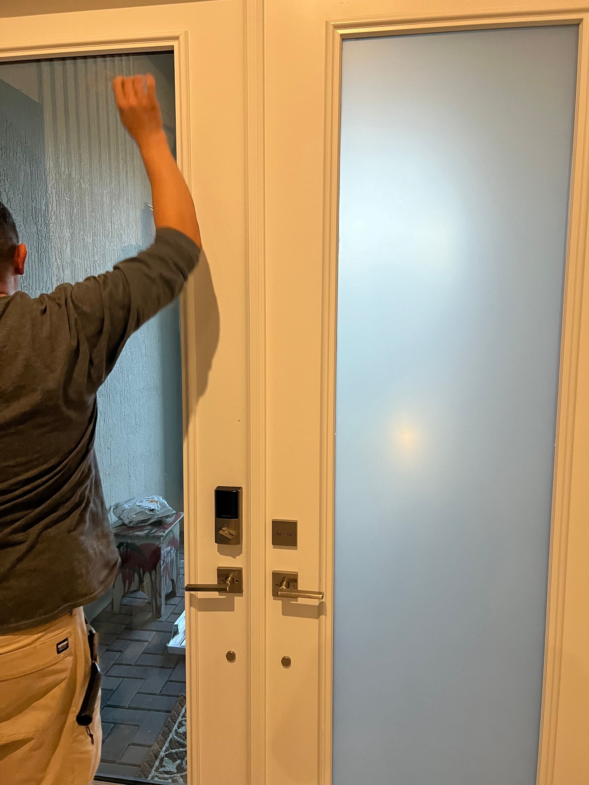A man is standing in front of a door and knocking on it.