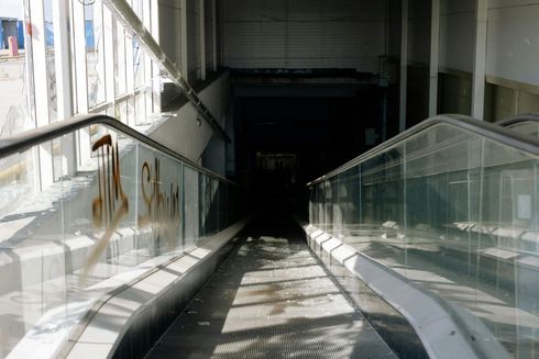 An escalator is going down a dark hallway in a building.