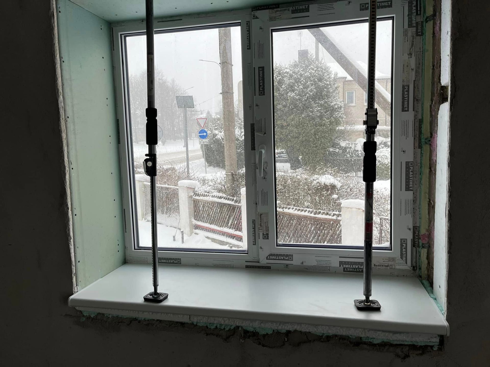 Statomas langas su vaizdu į apsnigtą lauką.