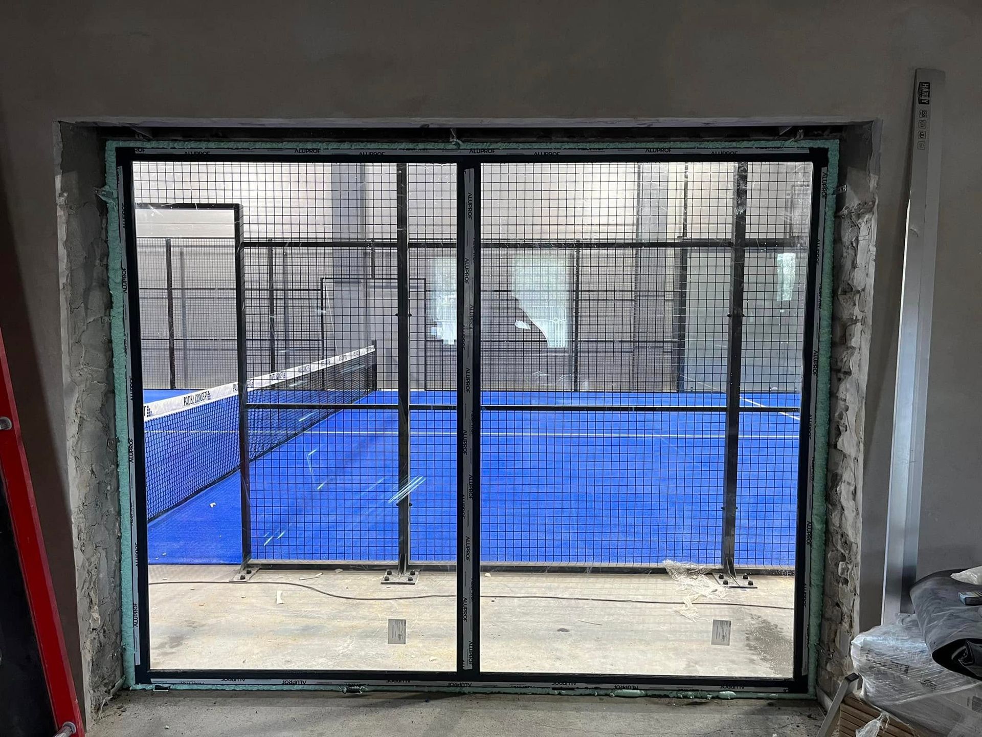 Stumdomos stiklinės durys vedančios į padelio teniso kortą.
