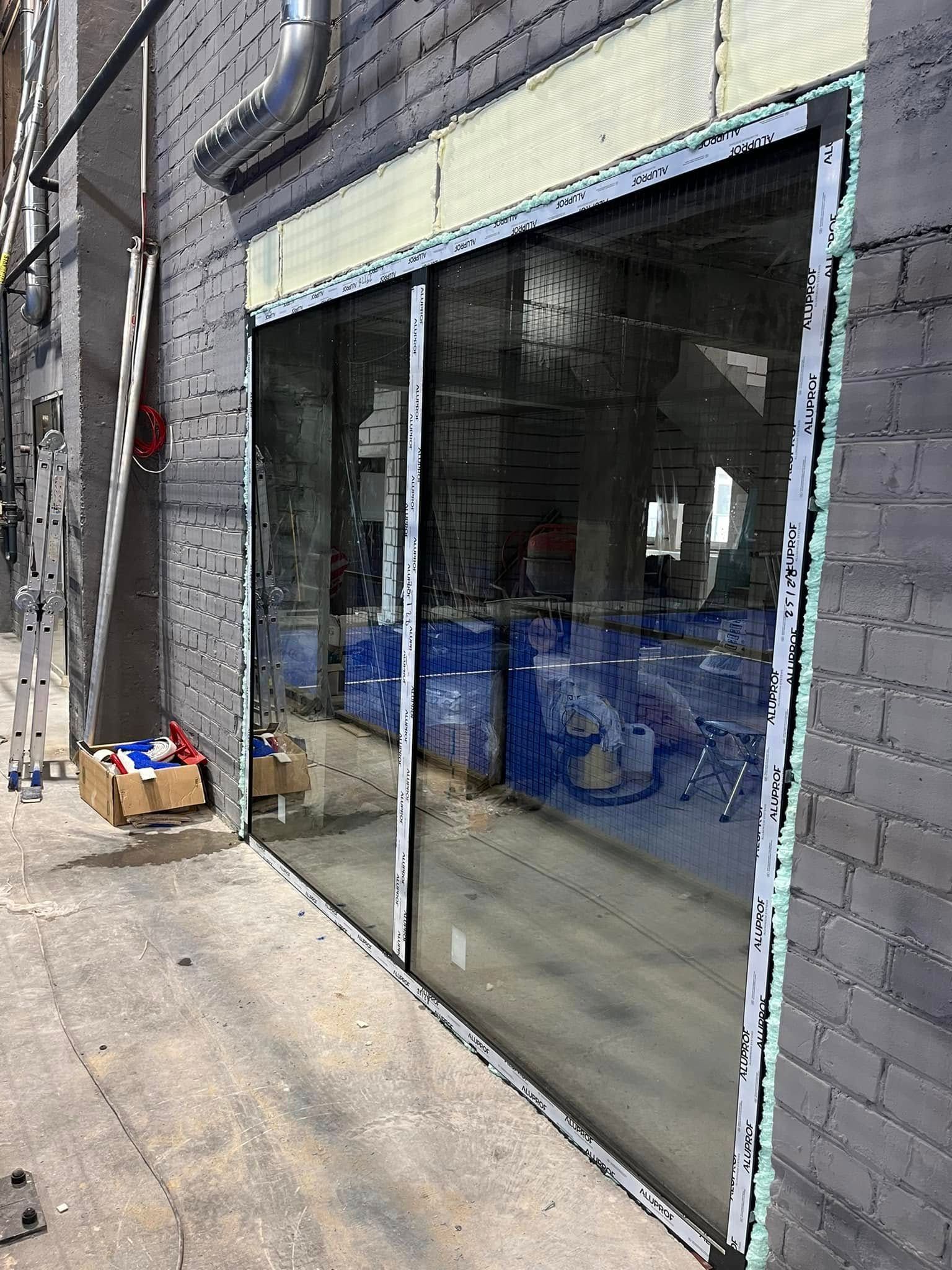 Ant mūrinio pastato montuojamos stumdomos stiklinės durys.