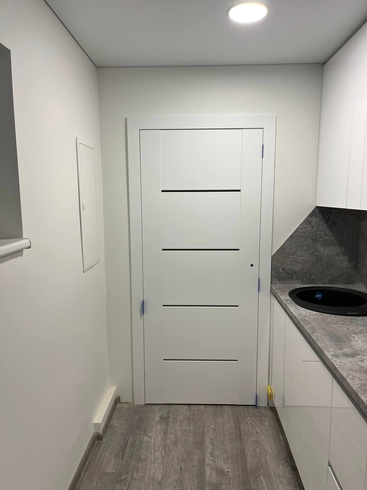 Virtuvė su baltomis spintelėmis ir baltomis durimis