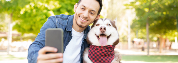 A man is taking a selfie with his dog in a park.