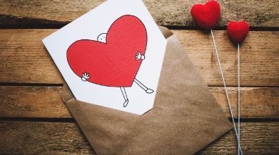 A card with a heart on it is in an envelope on a wooden table.