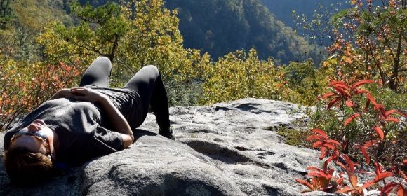 A person is laying on a rock in the woods.