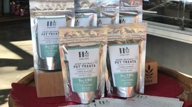 A bunch of bags of pet treats are sitting on top of a wooden table.