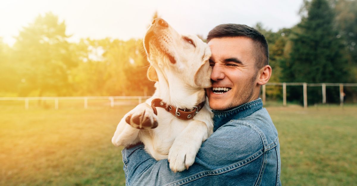 A man is holding a puppy in his arms and kissing it on the nose.