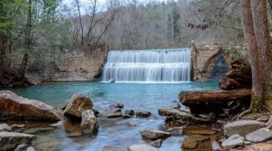 A waterfall in the middle of a forest surrounded by rocks and trees.