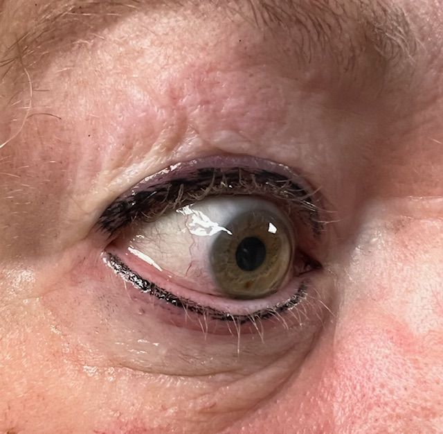 Close-up of two light blue eyes with eyeliner, mascara, and fair skin, looking forward.