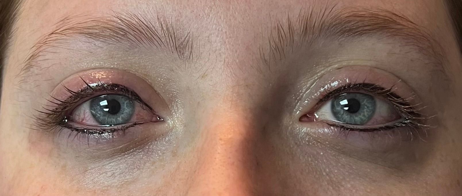 Close-up of two light blue eyes with eyeliner, mascara, and fair skin, looking forward.