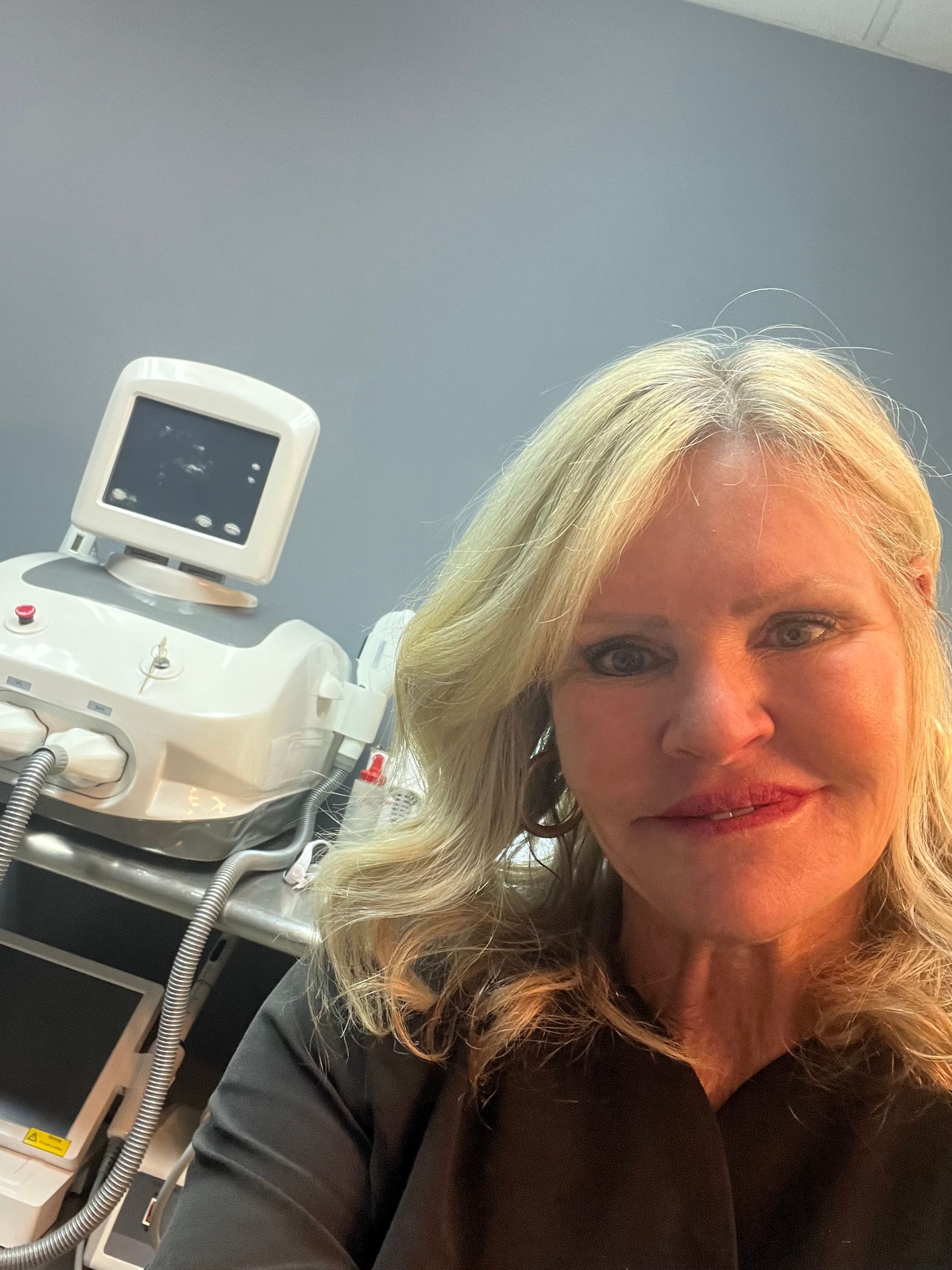 Woman in clinic with medical equipment, smiling.