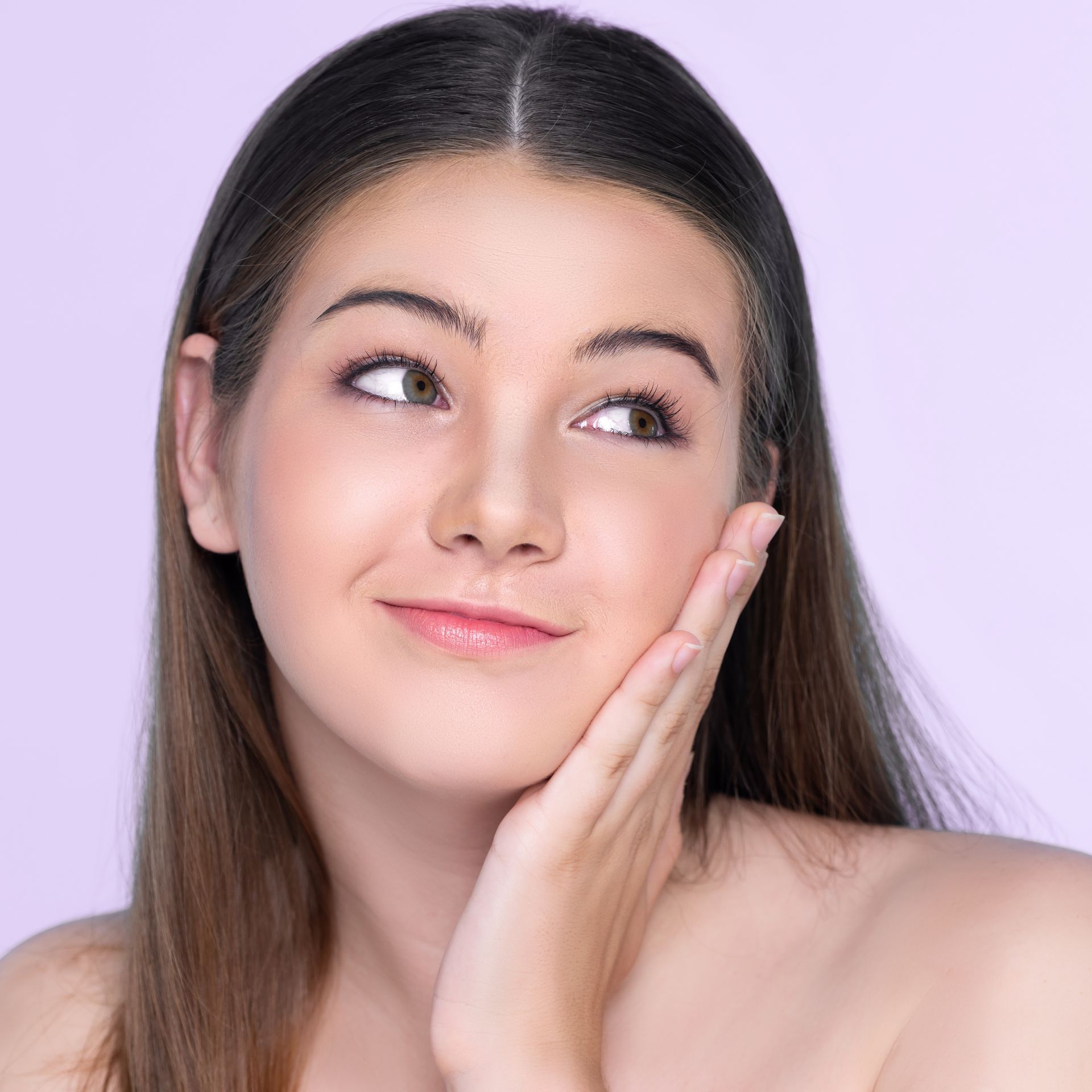Woman touching her cheek, looking upward with a thoughtful expression; lilac background.