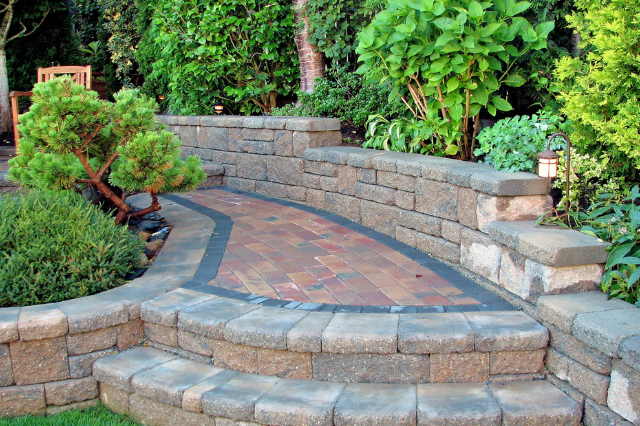 A lawn with a concrete curb surrounded by rocks and bushes