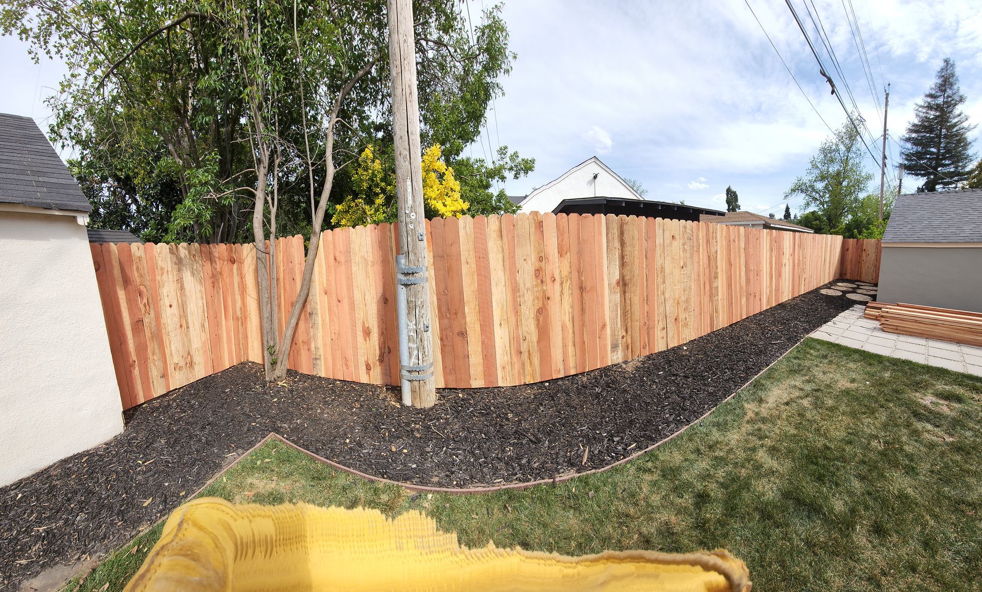 A wooden fence is in the backyard of a house.