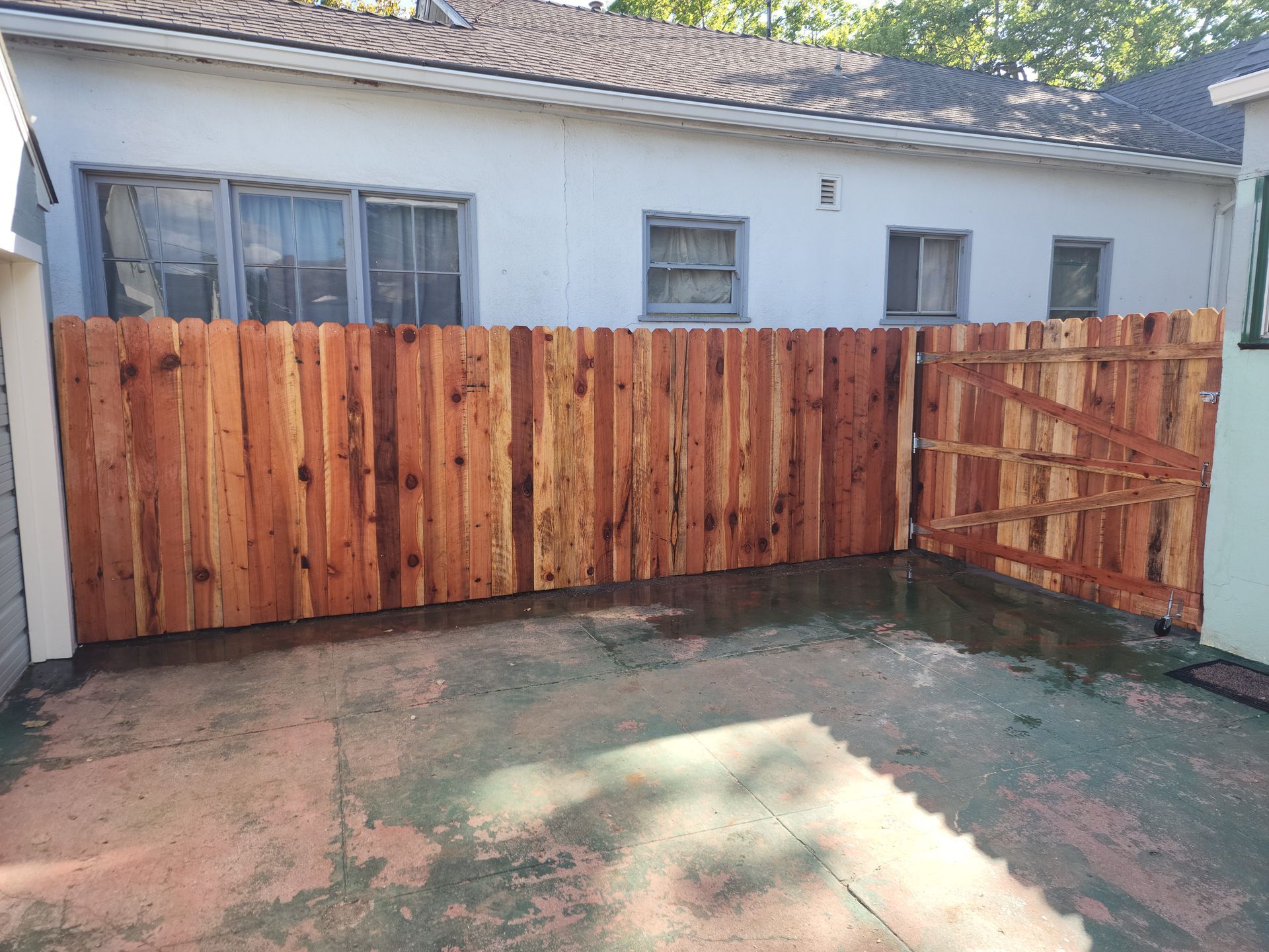 A wooden fence is in the backyard of a house.