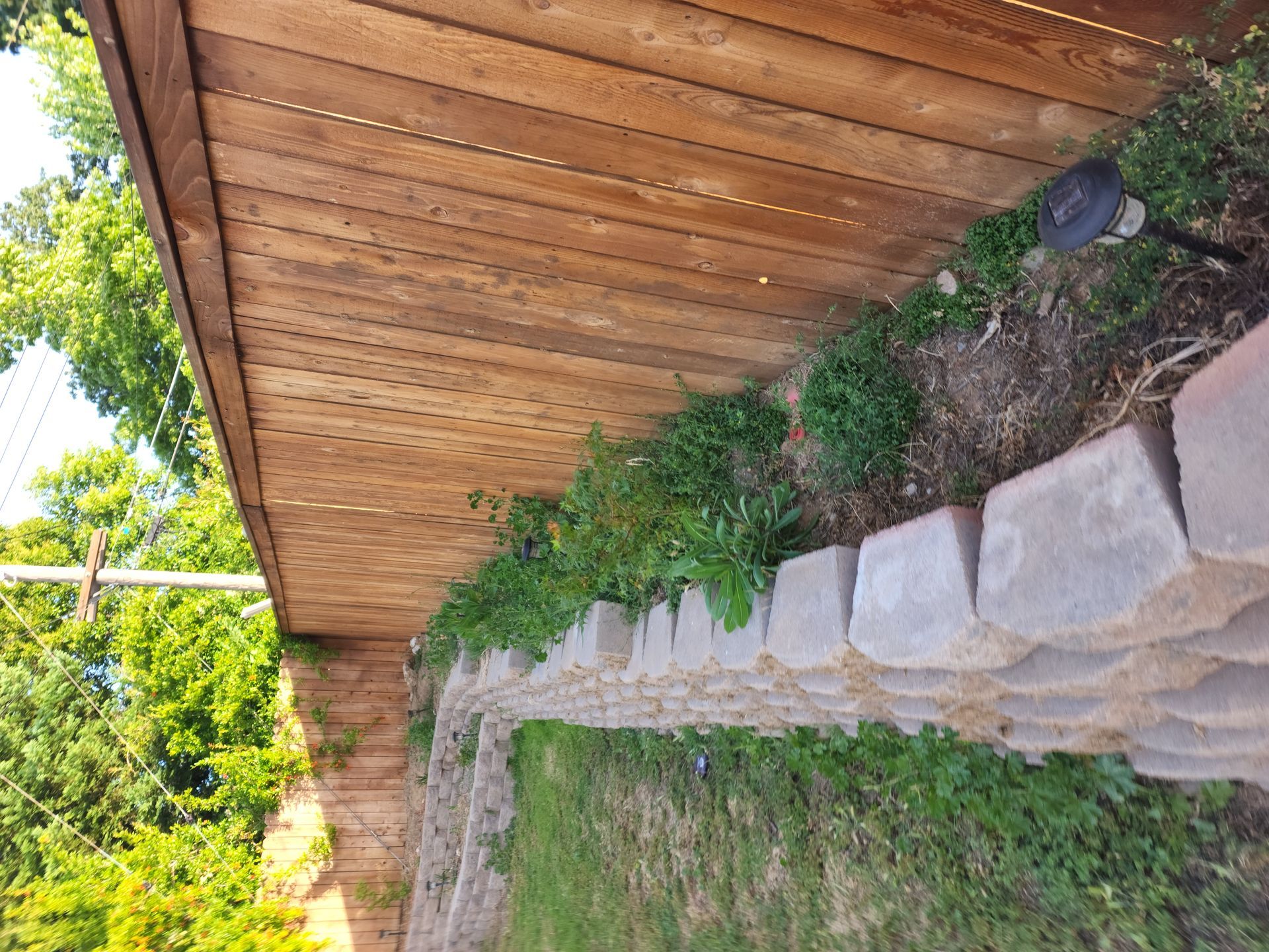 A wooden fence surrounds a stone wall in a yard.