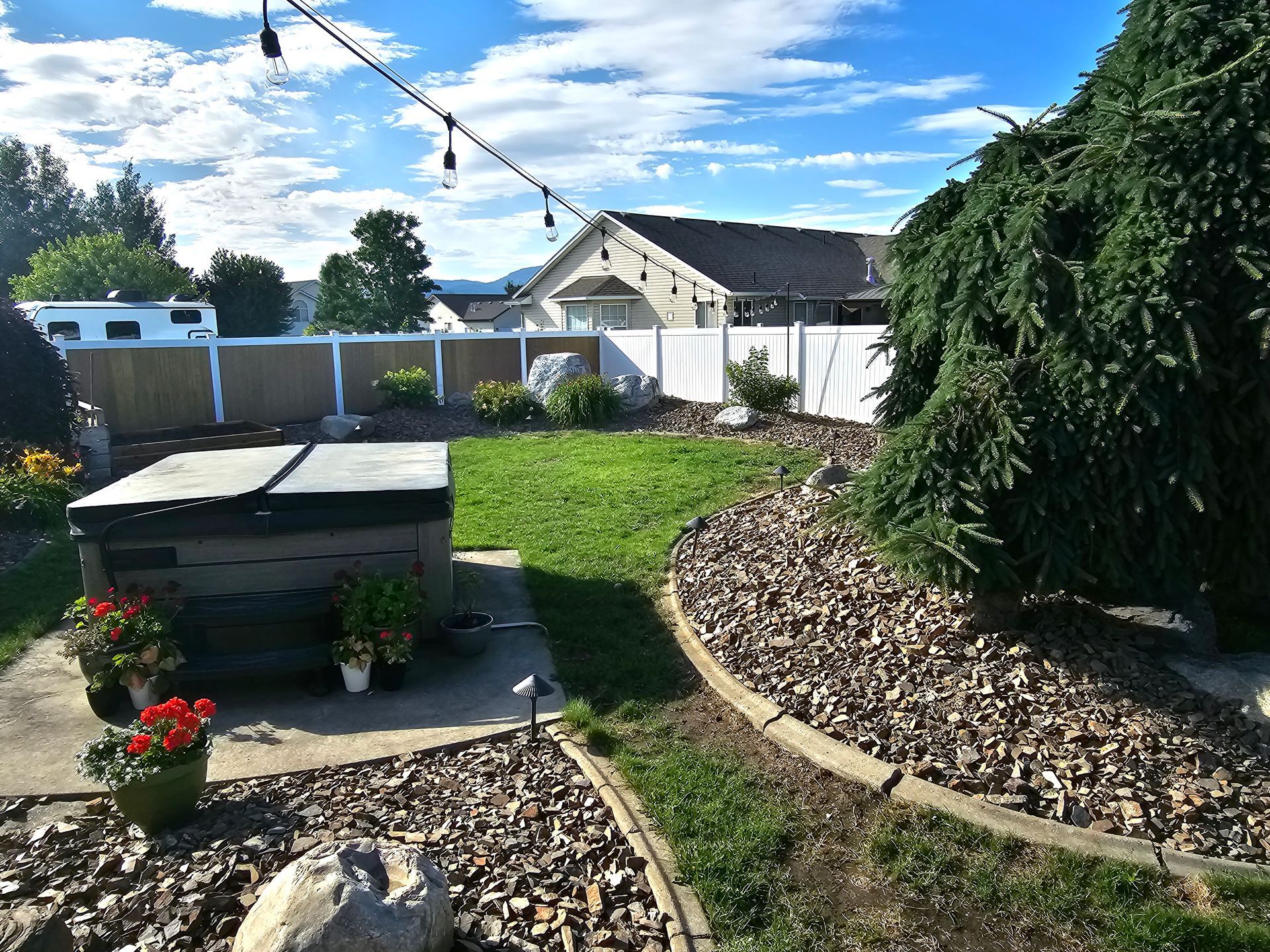 A backyard with a hot tub and a house in the background