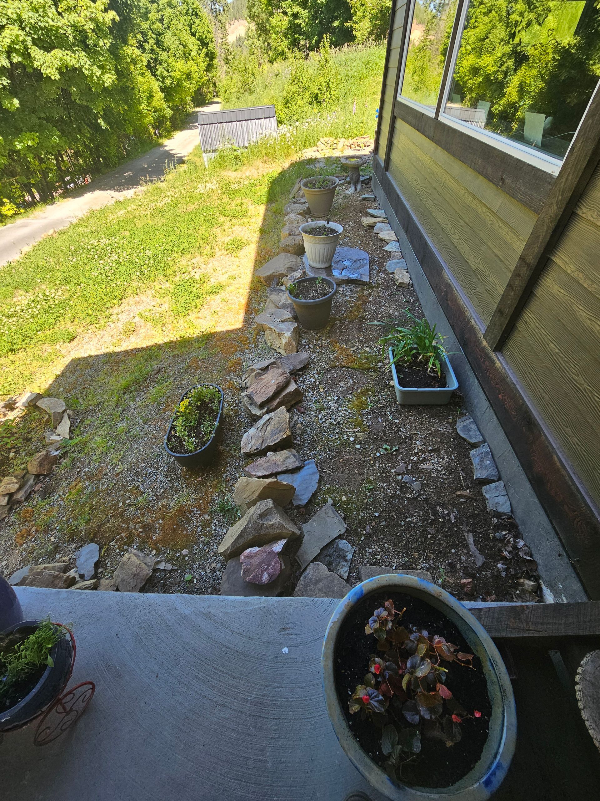 A view of a garden from a balcony with potted plants and rocks.