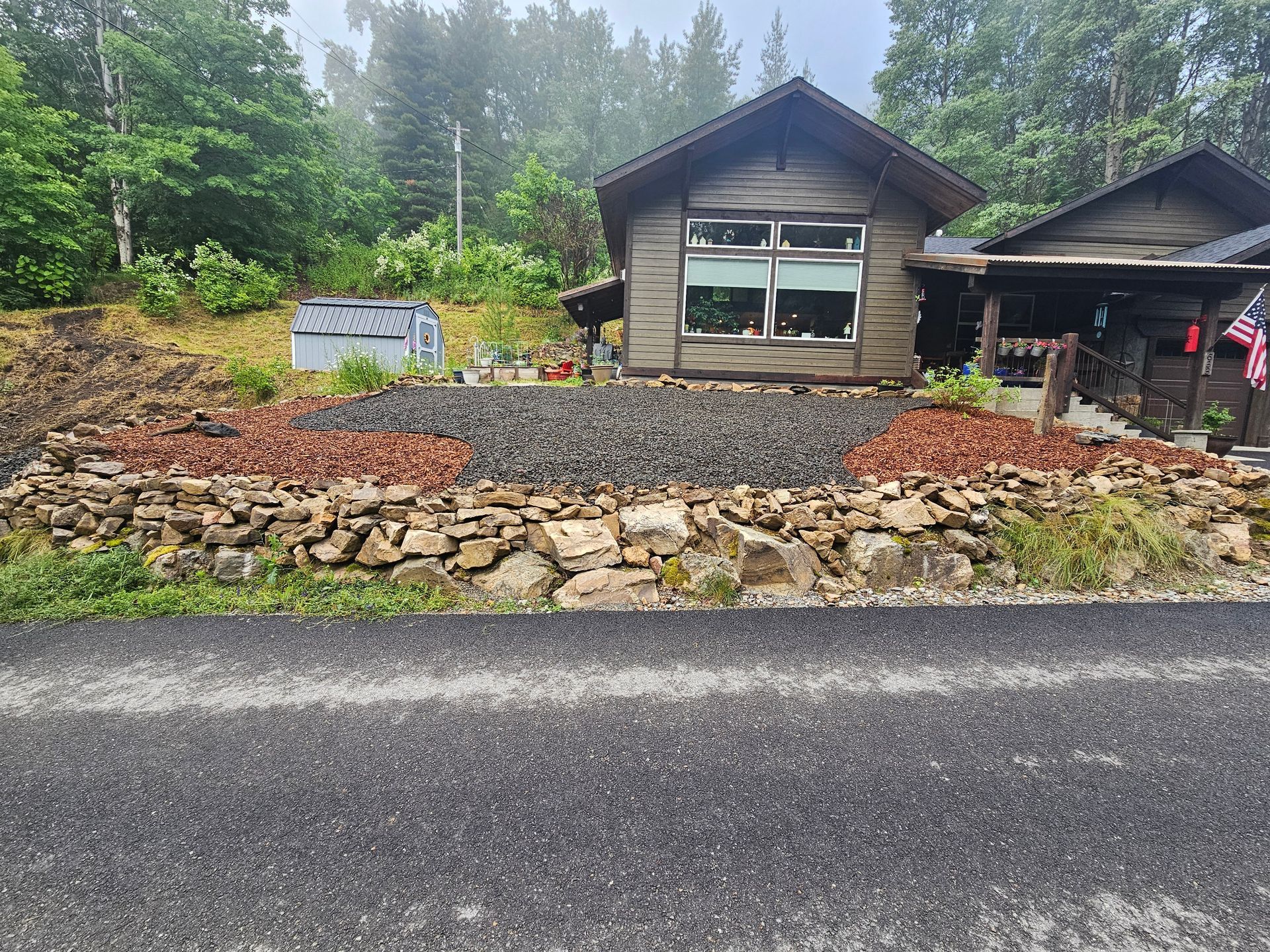 A small house is sitting on the side of a road next to a stone wall.