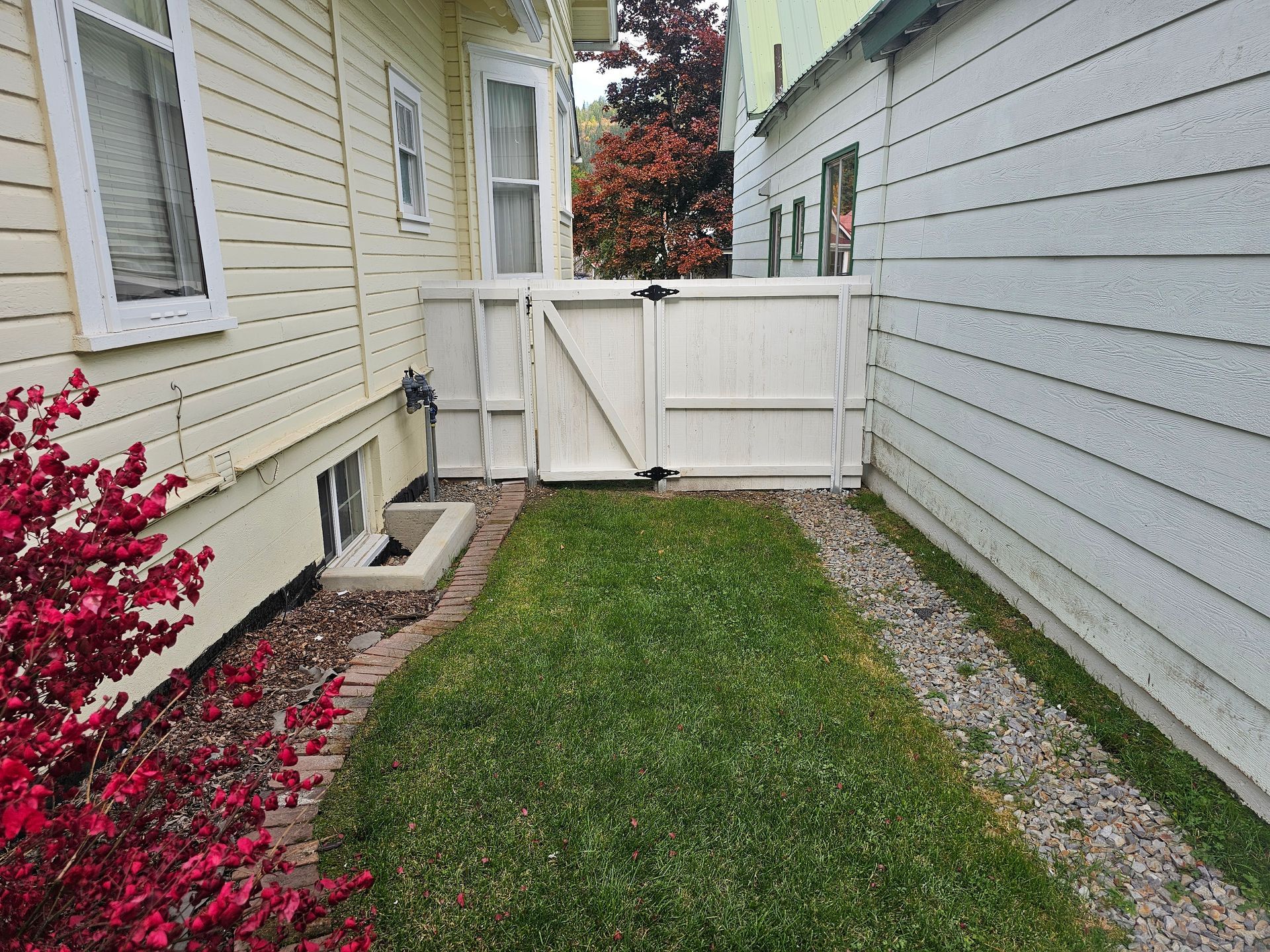 There is a white fence in the backyard of a house.