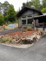 A small house is sitting on top of a hill next to a road.