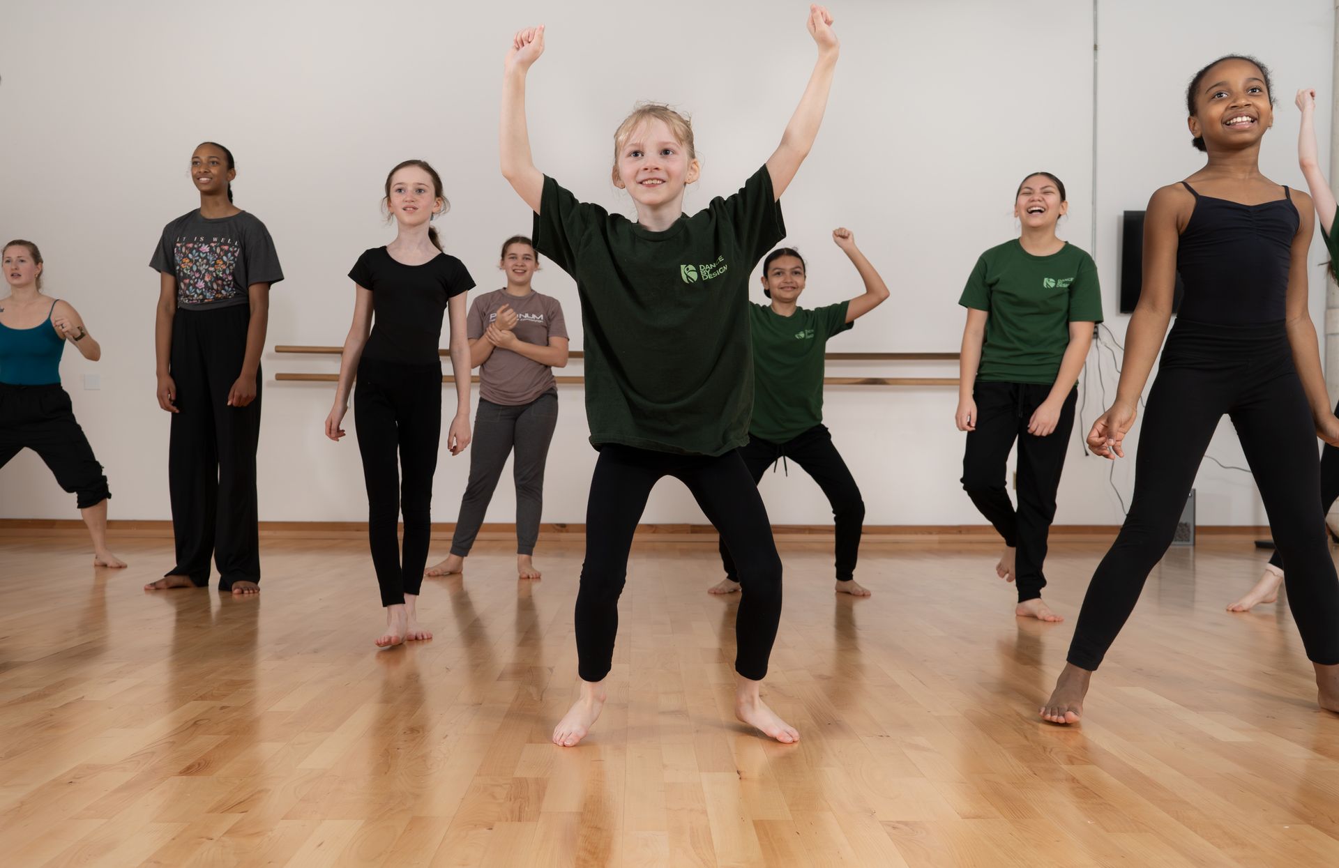 Two dancers in a studio, embracing. One in purple and black, the other in purple.