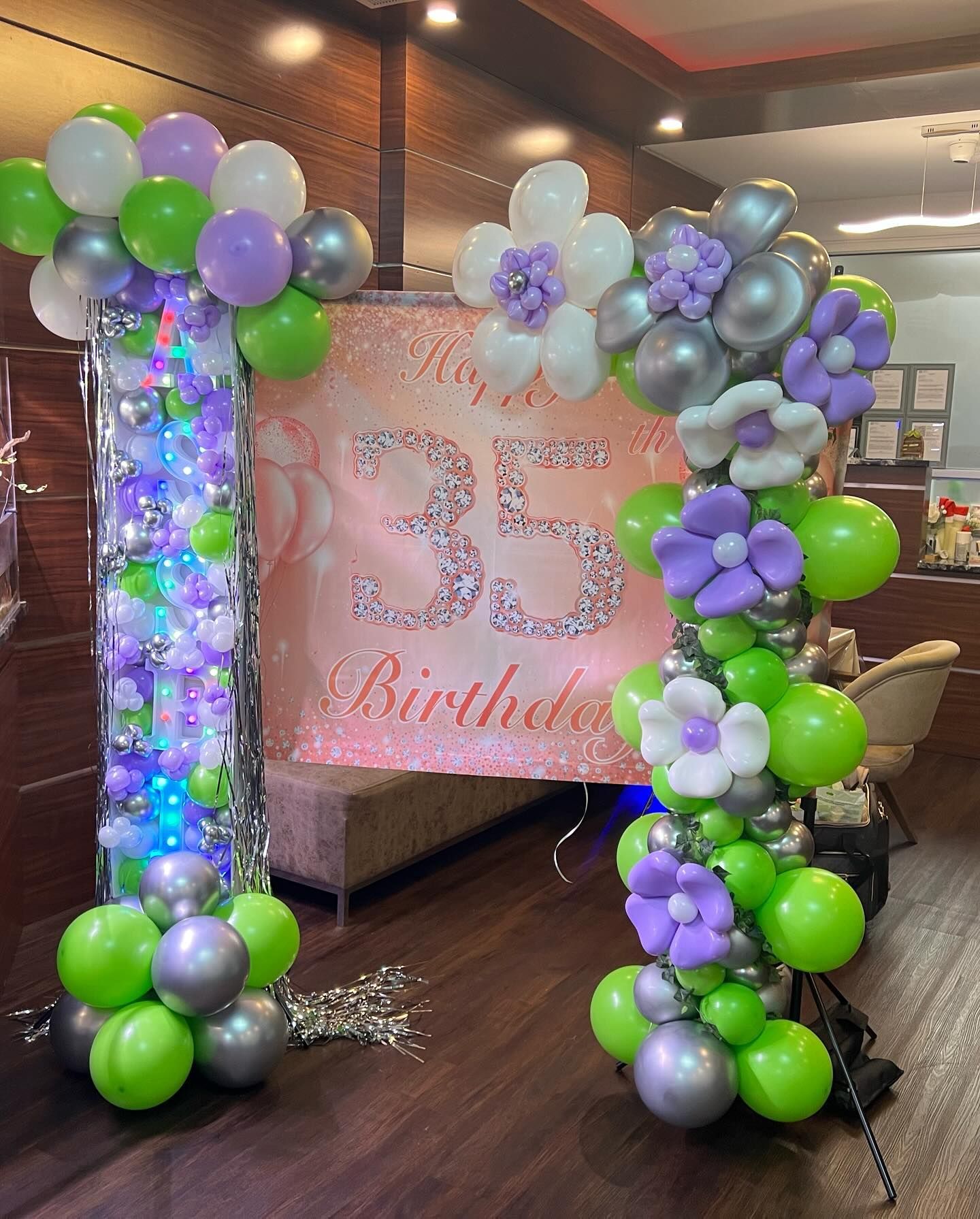 A room decorated with balloons and flowers for a 35th birthday.
