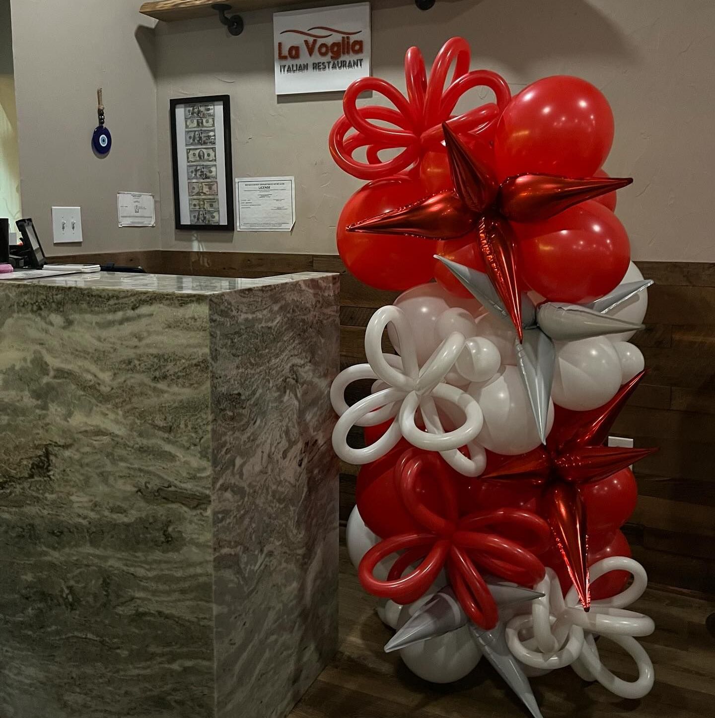 A bunch of red and white balloons in front of a la voglia sign