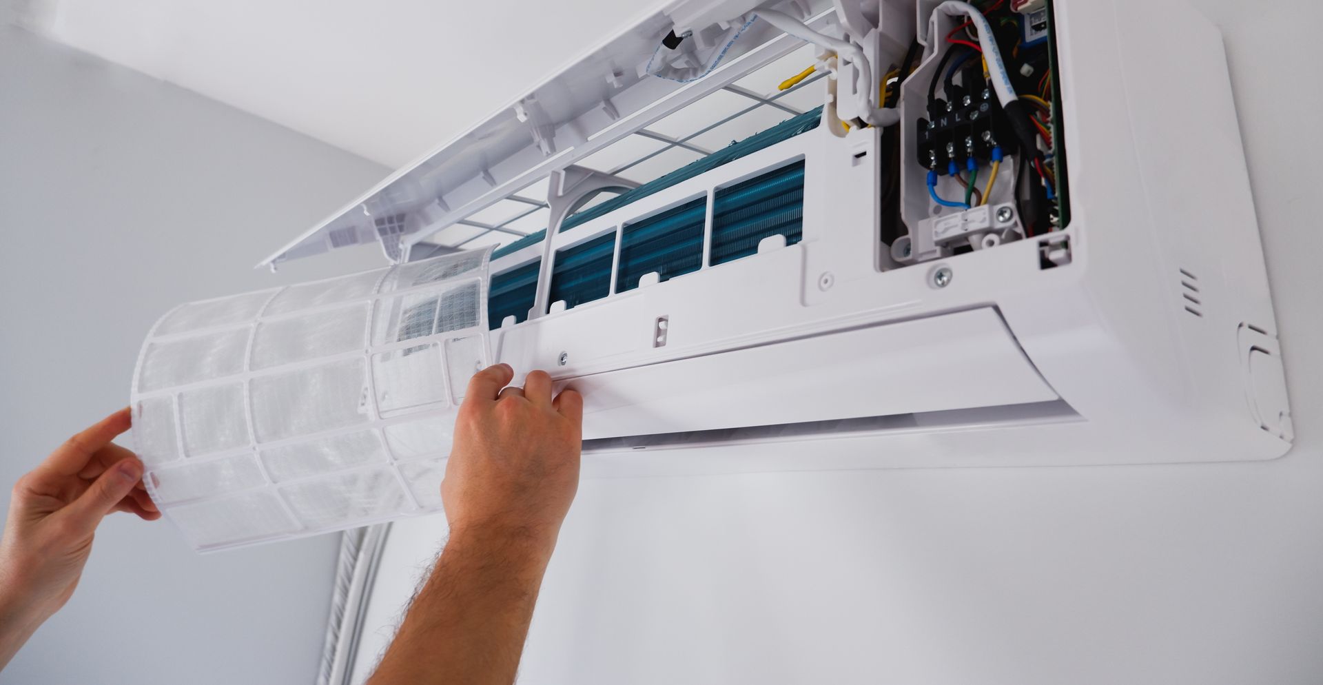 A person is cleaning the filter of an air conditioner.