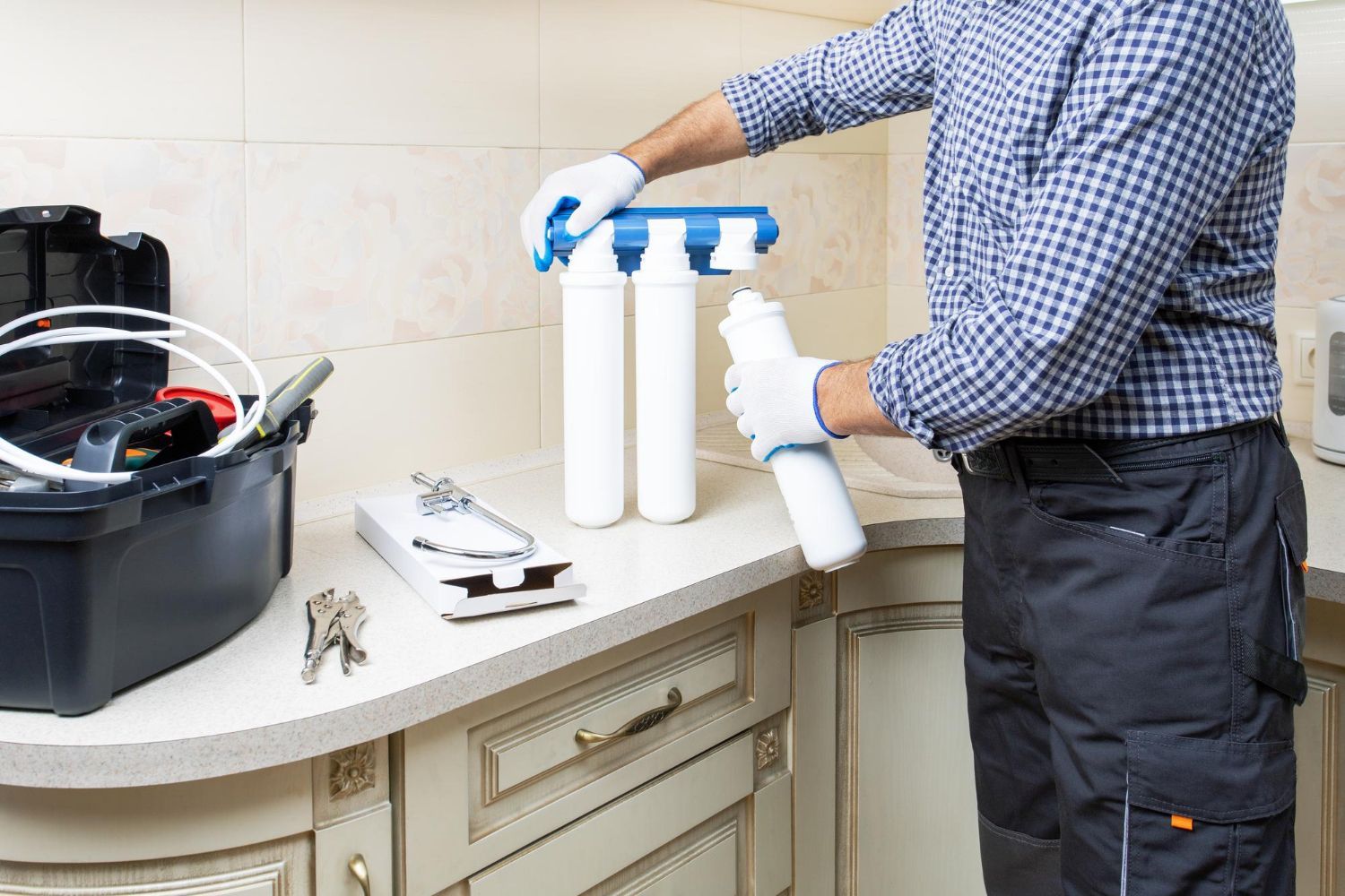 A man is installing a water filter in a kitchen.