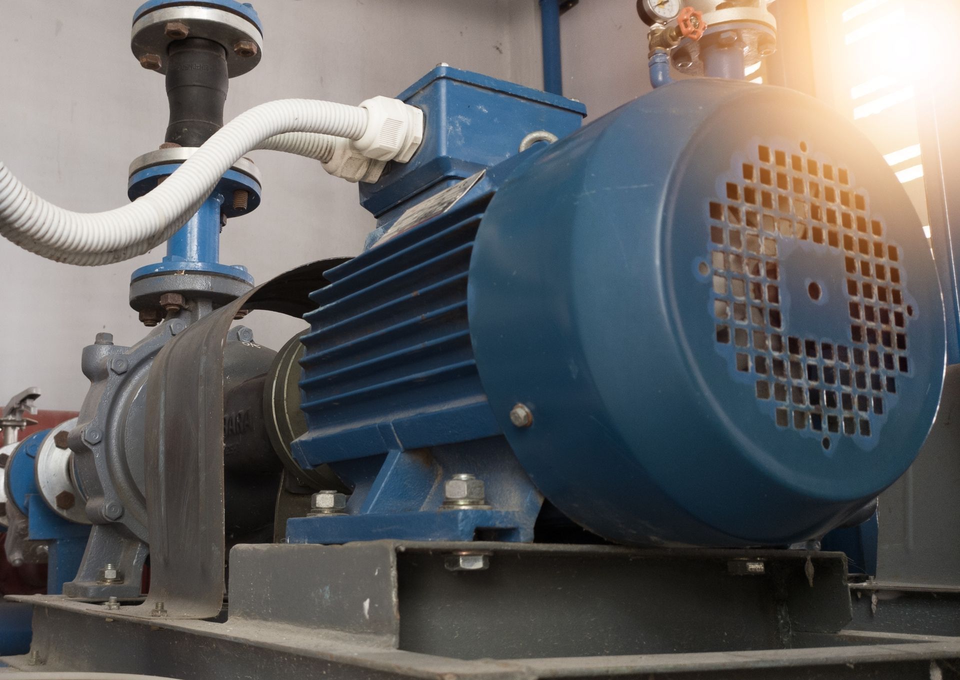 A blue electric motor is sitting next to a water pump in a room.