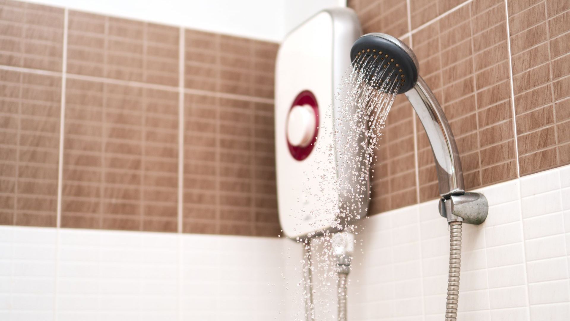 A close up of a shower head in a bathroom with water coming out of it.