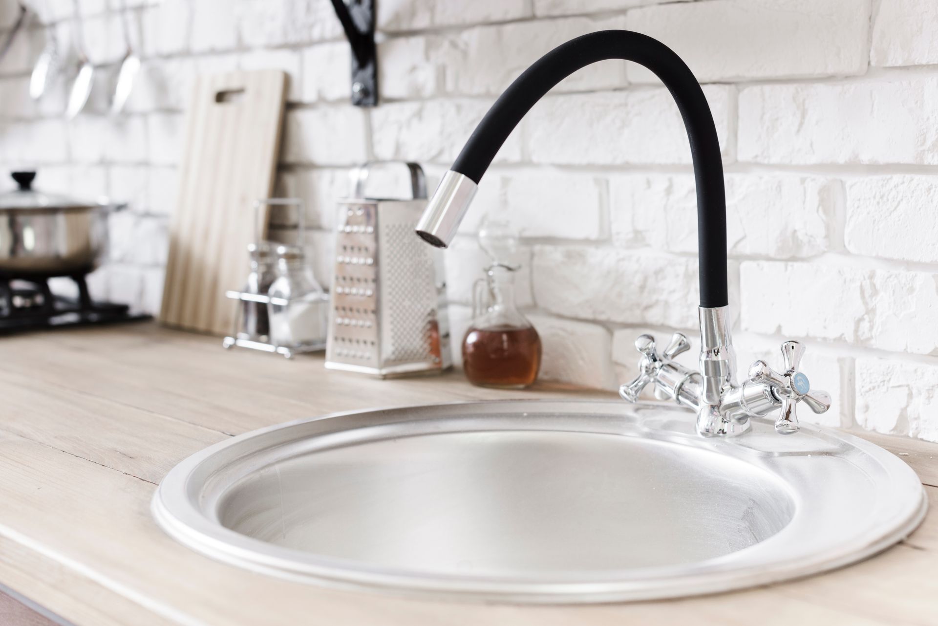 A kitchen sink with a black faucet on a wooden counter.