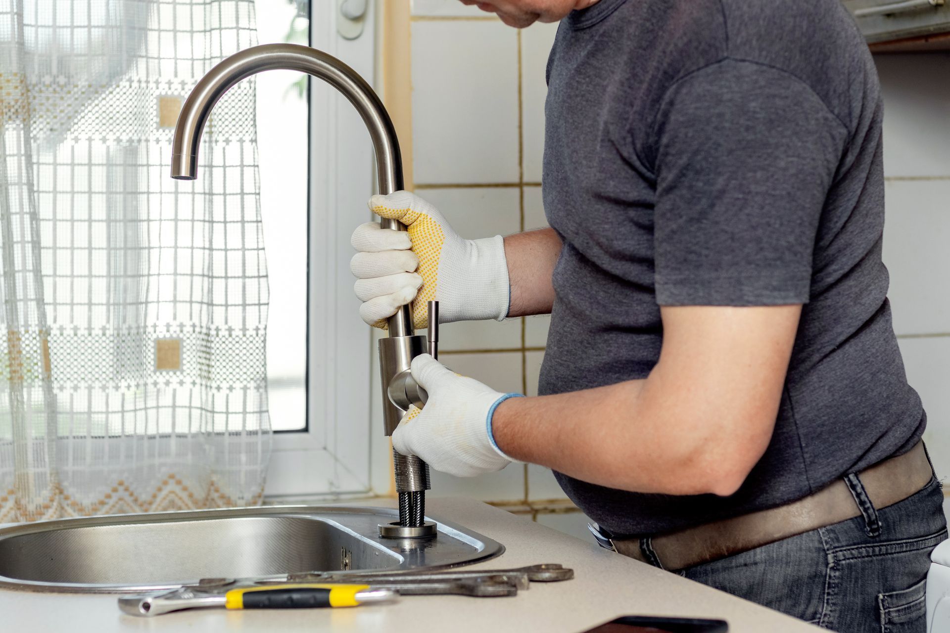 A man is fixing a faucet in a kitchen.