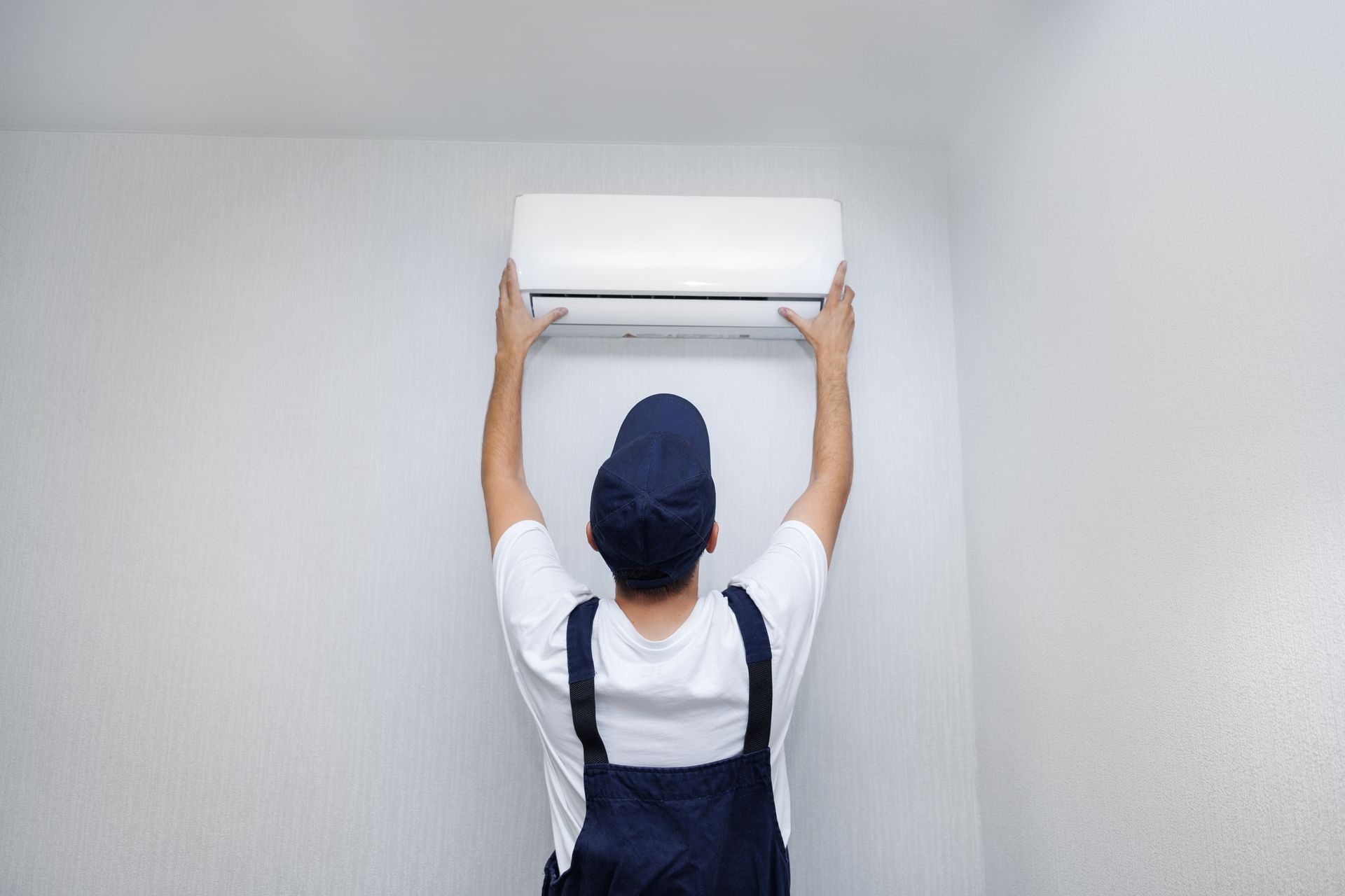 A man is installing an air conditioner on the wall.