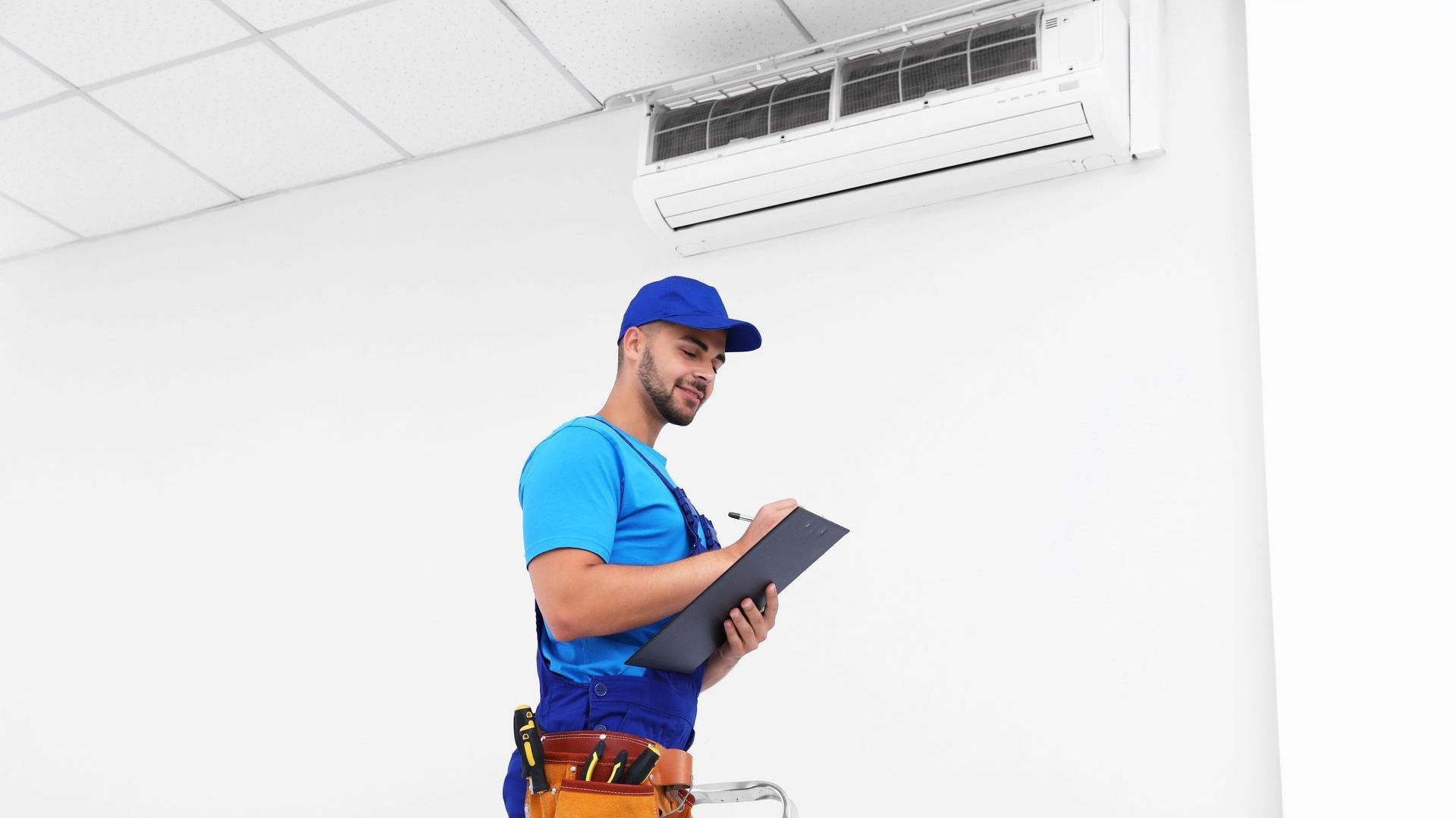 A man is standing on a ladder looking at a clipboard.