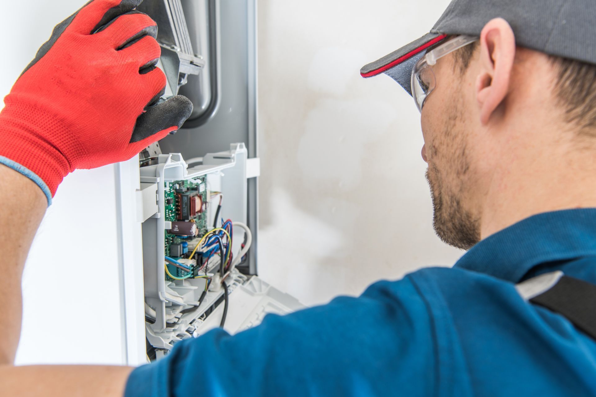A man is working on a boiler with a screwdriver.