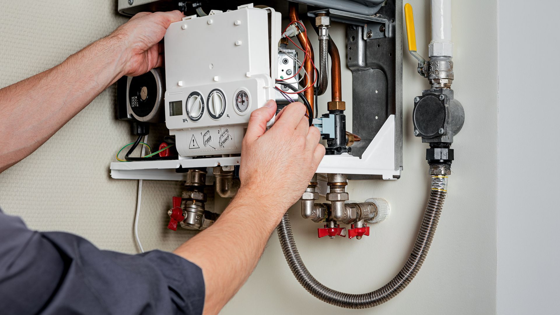A man is fixing a boiler with a wrench.