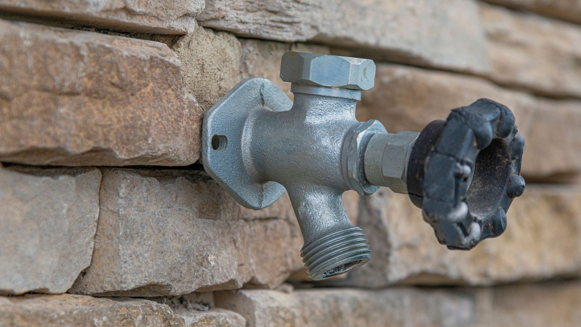 A faucet is attached to a brick wall.