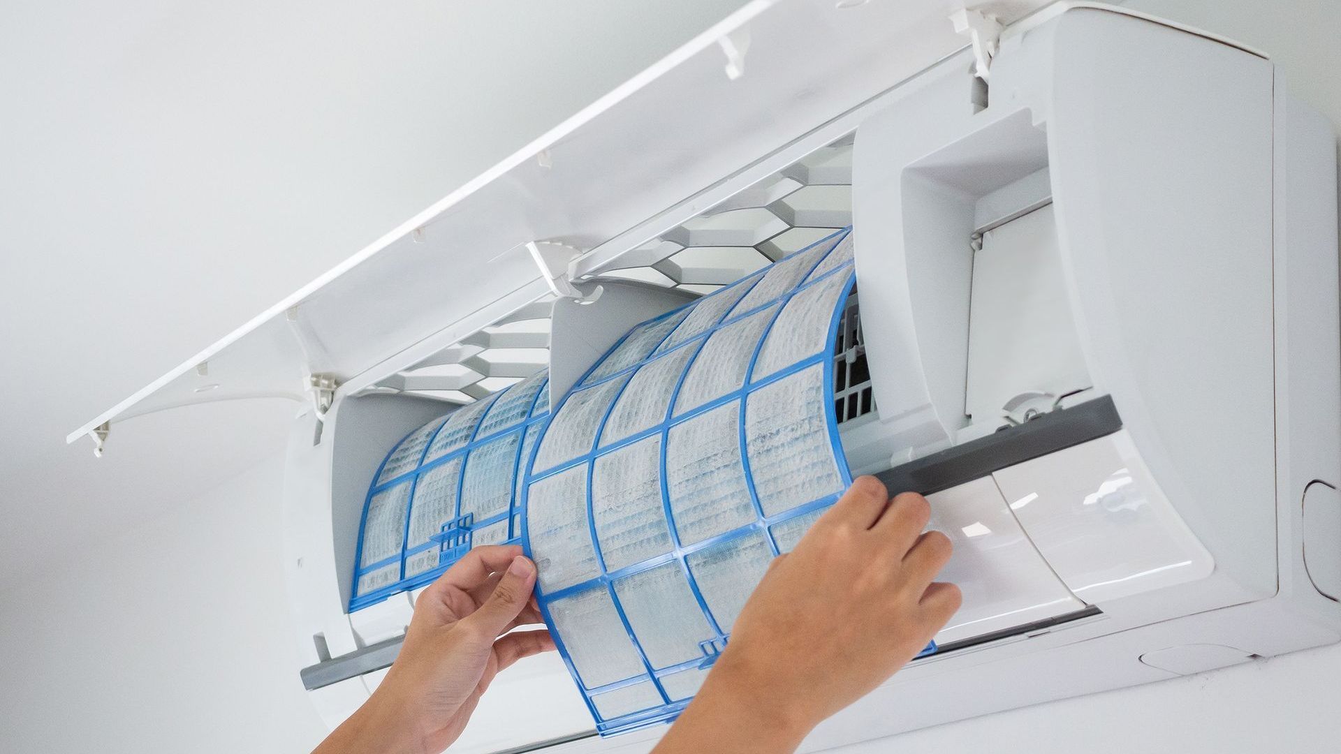 A person is cleaning the filter of an air conditioner.
