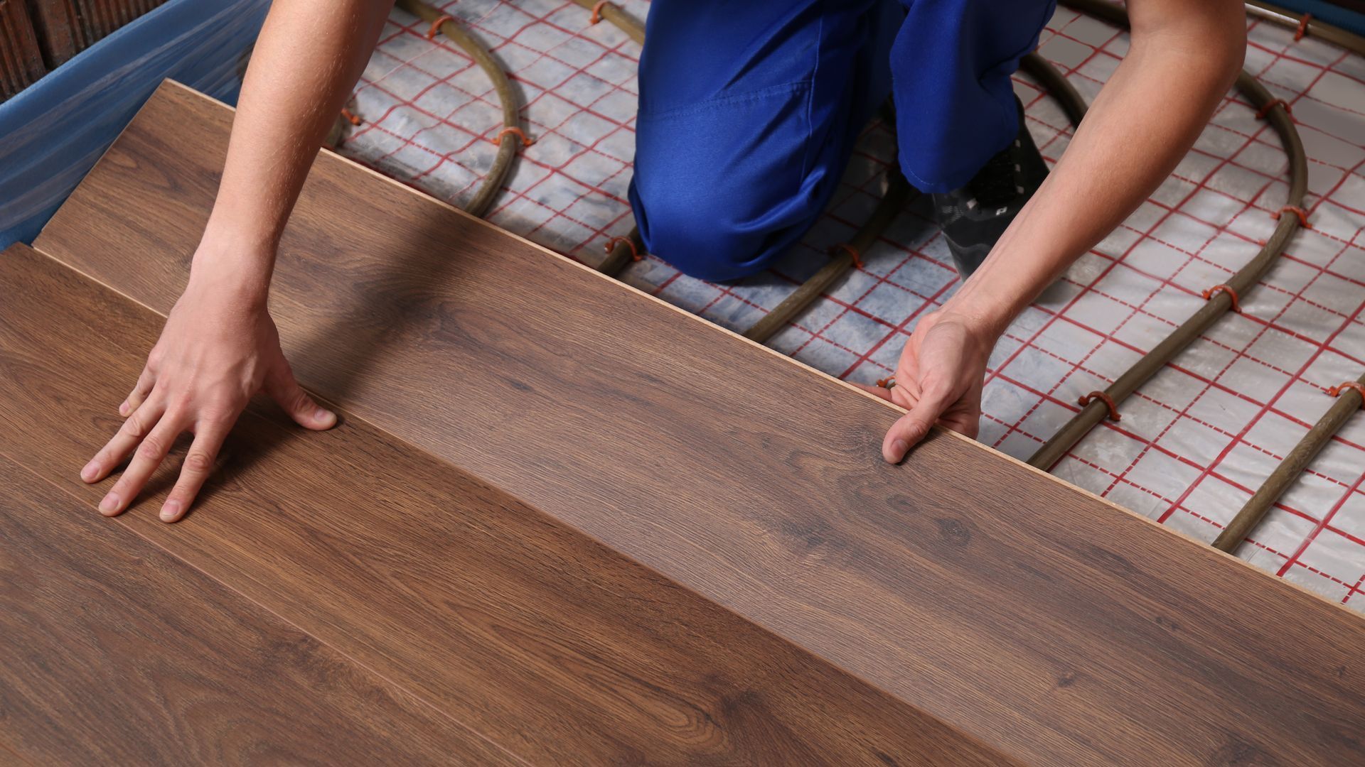 A person is installing a wooden floor in a room.