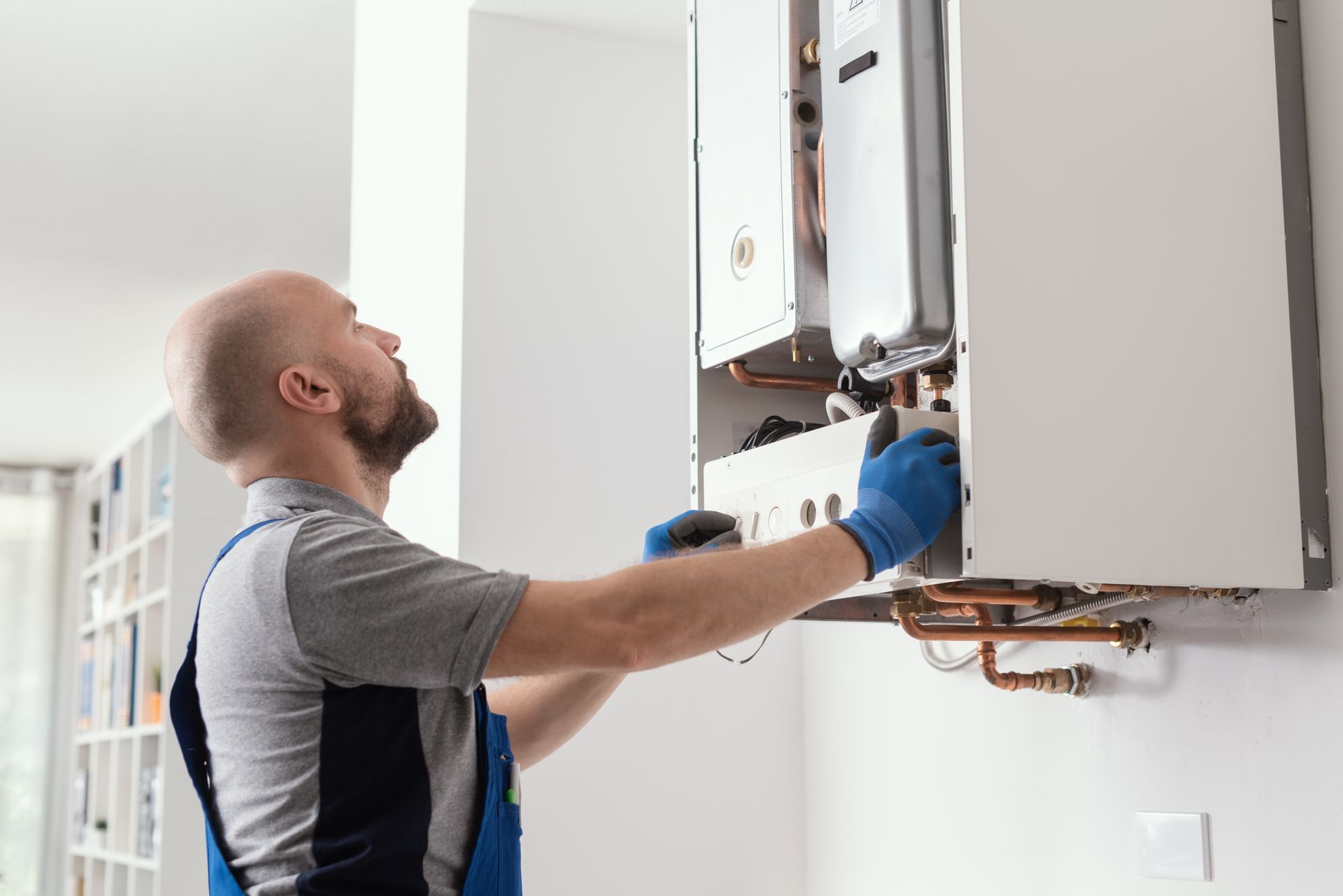 A man is fixing a boiler in a living room.
